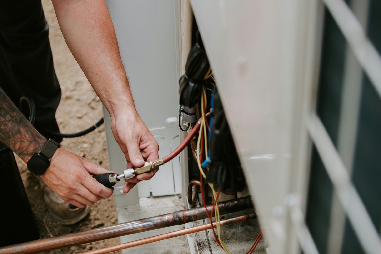 Technician's hands connecting a refrigerant gauge hose during a repair